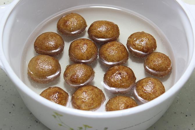 adding fried balls to syrup to make bread gulab jamun
