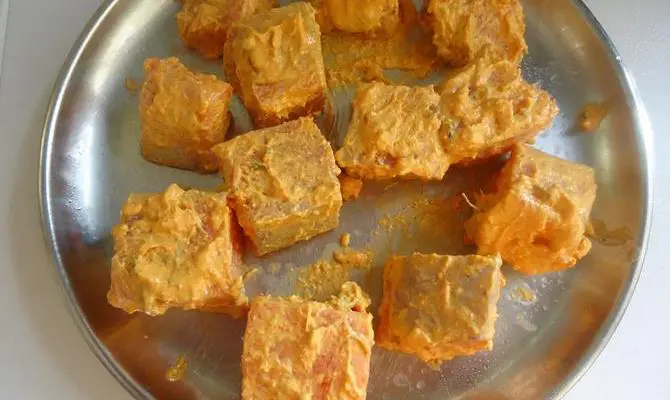 applying marinade to meat for resting fish tikka