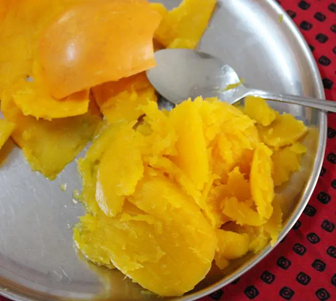 scooping the pulp to make pumpkin kheer recipe