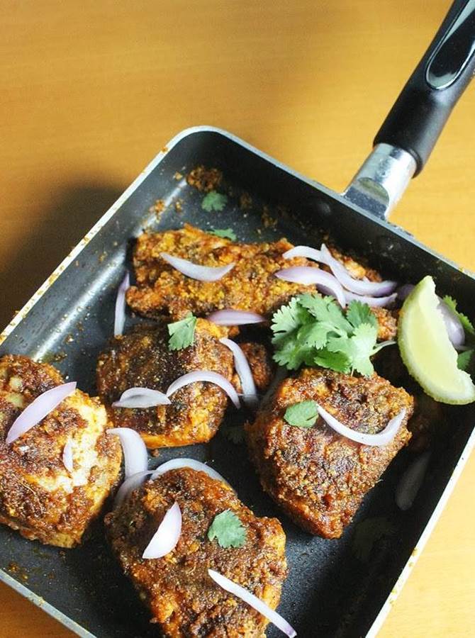 flipping roasting fillets on pan to make amritsari tawa fish fry