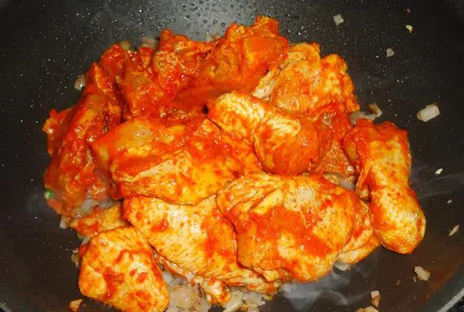 frying marinated chicken in onions to make andhra chicken curry recipe