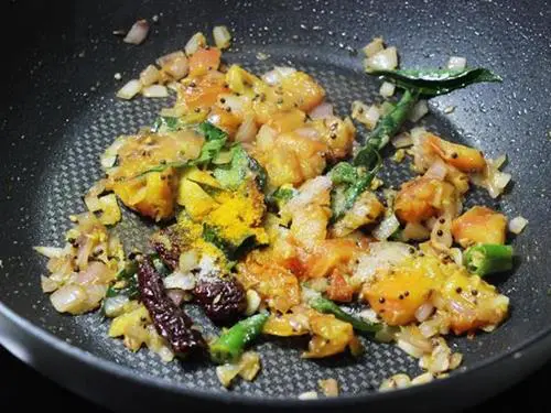 adding turmeric and salt to fry tomatoes