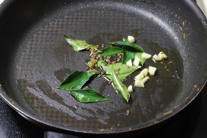 frying garlic in a pan for tempering prawn curry