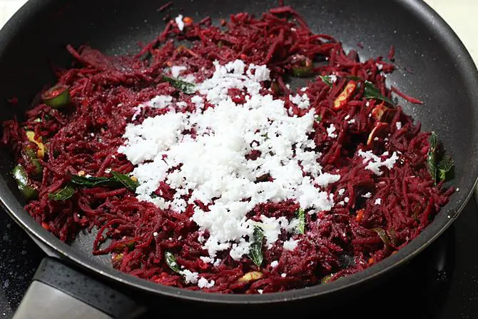 addition of grated coconut to pan for beetroot stir fry