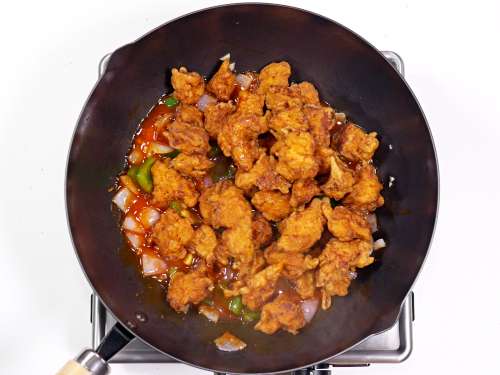 adding fried chicken to the chili sauce