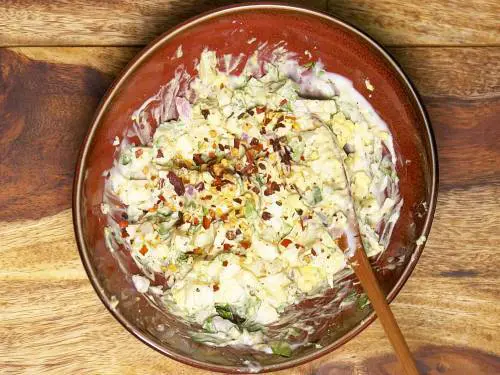 adding chilli flakes to creamy egg salad