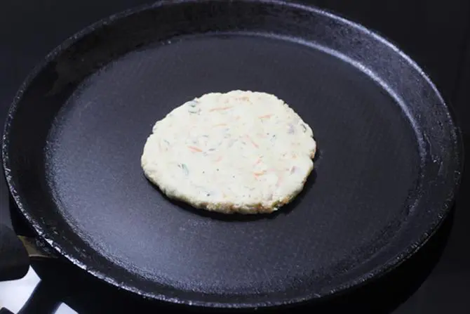 spreading rice dough on a pan to make akki roti