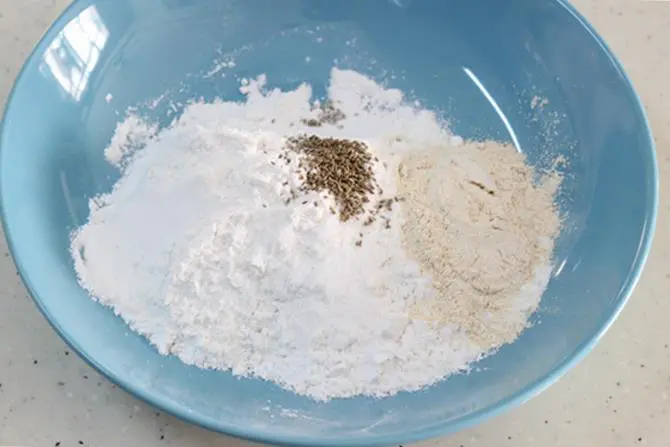 Add uraddal flour, ajwain (omam/ vammu), chilli powder, sesame seeds and salt