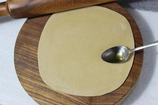 smearing ghee over ajwain paratha