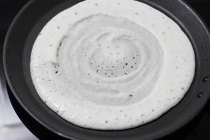 spreading batter to make egg dosa recipe