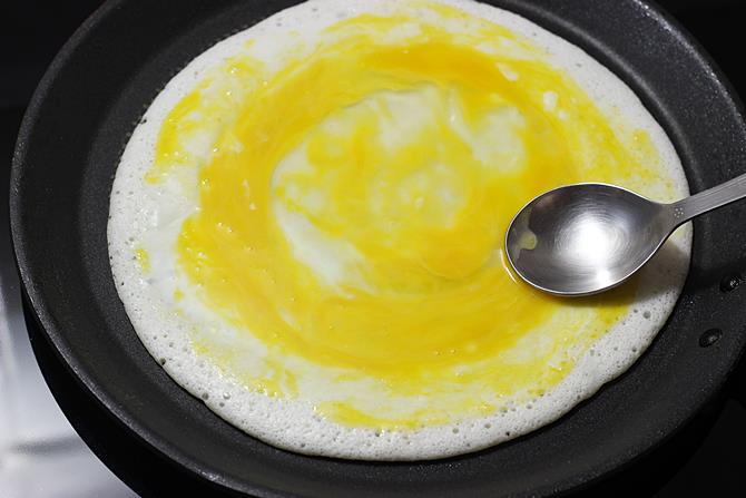 spreading yolk on egg dosa