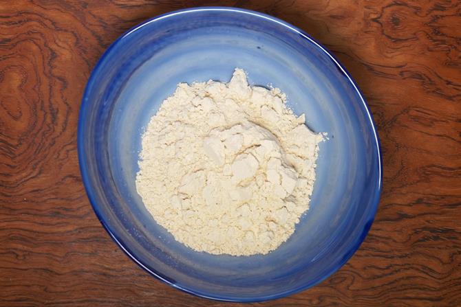 adding wheat flour to mixing bowl for mysore bonda recipe
