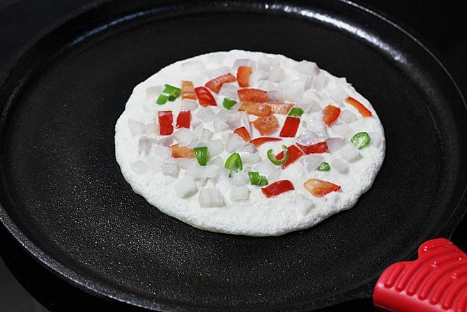 adding veggies to make rava uttapam