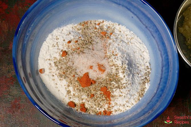 Add flour, red chili powder, salt, hing, sesame seeds, carom seeds