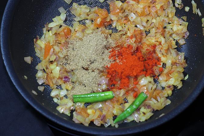 adding spice powders to to onions tomatoes
