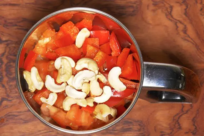 adding tomatoes cashews capsicum to make paneer do pyaza