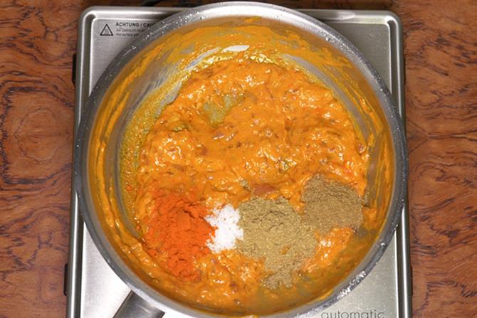 adding spice powders to onion tomato masala for paneer do pyaza