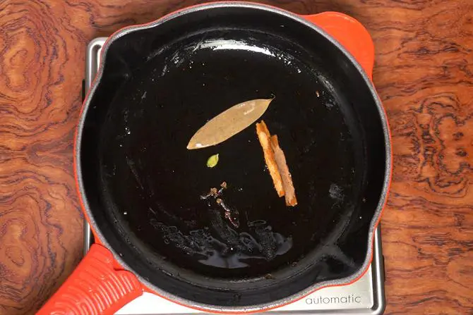 adding spices to make chicken korma