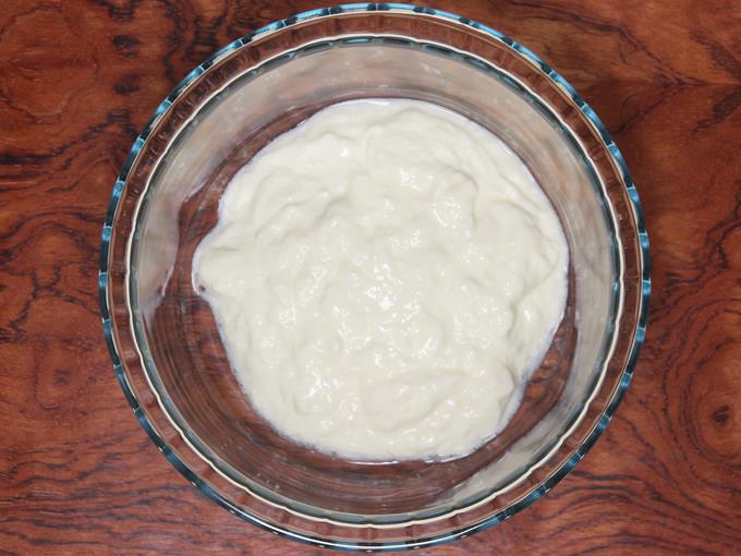 adding curd to a bowl to make lassi