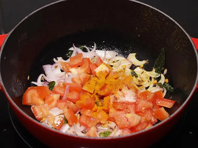 Adding tomatoes to make poori curry
