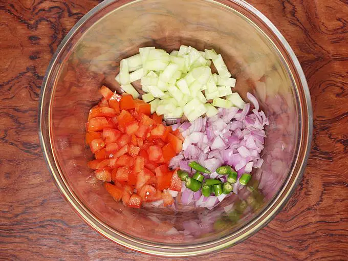 adding onions, tomatoes, cucumber and green chilies