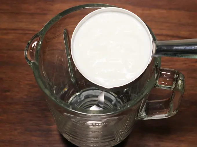 adding curd to a blender to make lassi
