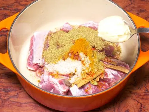 adding ingredients to a pot to make goat korma marinade 