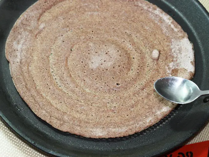 drizzling oil to cook ragi dosa