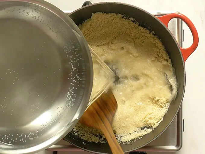 pouring suji in a stream for rava kesari recipe