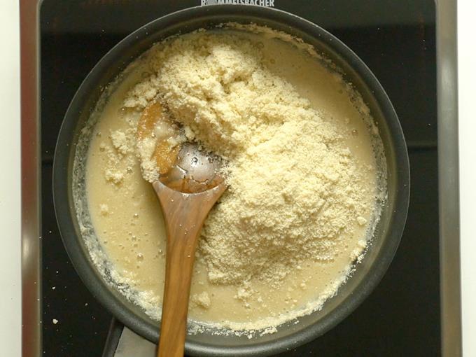 adding cashew powder to syrup to make kaju katli