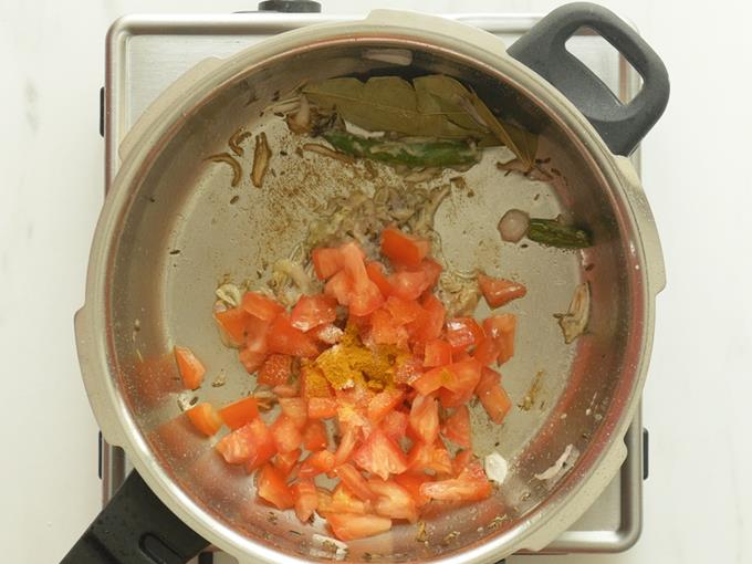 adding tomatoes to make mushroom biryani
