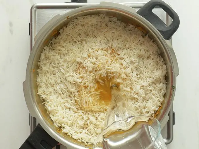 pouring water to make mushroom biryani