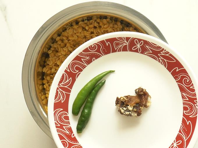 adding chilies tamarind to dal to make tomato pappu