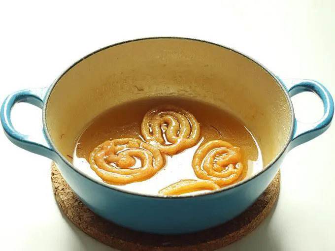 Adding jalebi to warm sugar syrup