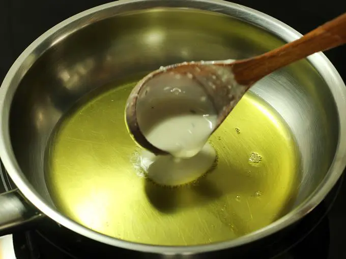 pouring batter to make malpua