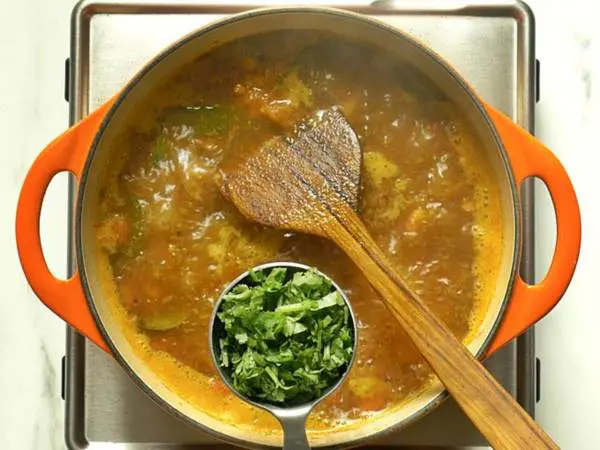 adding coriander leaves to rasam