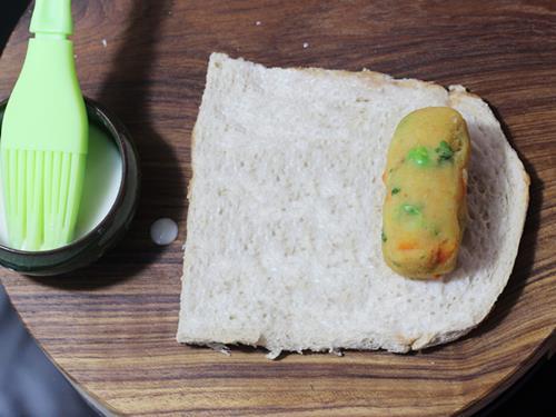 smearing milk over bread to make bread roll