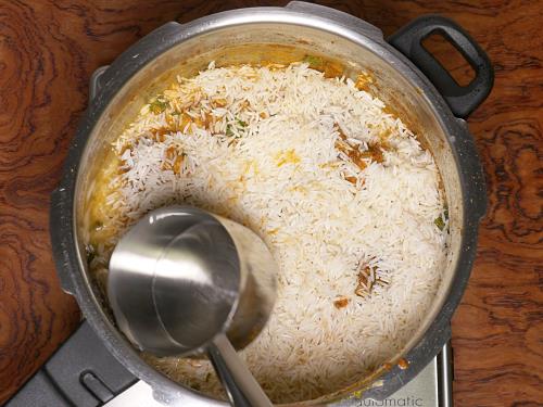 layering rice and pouring water to make chicken biryani