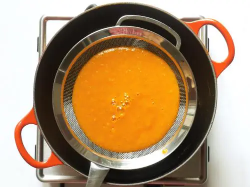 passing tomato soup through a strainer
