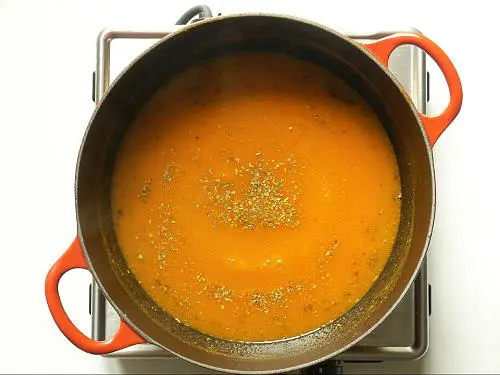 adding herbs to tomato soup