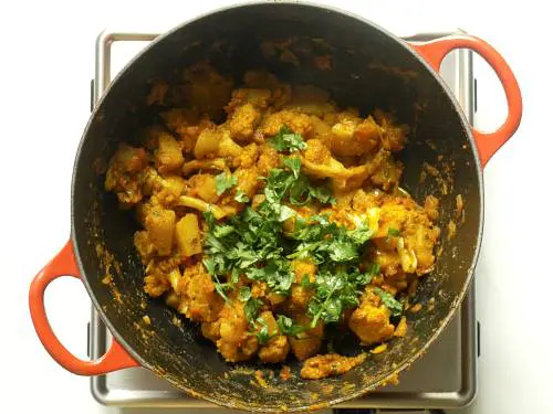 garnishing aloo gobi with coriander leaves 