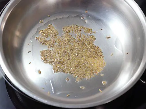 frying cumin in hot oil for potato curry