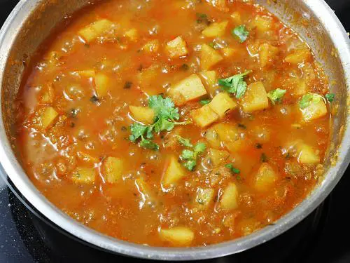 adding coriander leaves to potato curry
