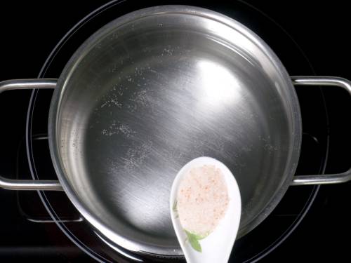 adding salt to pot to boil pasta