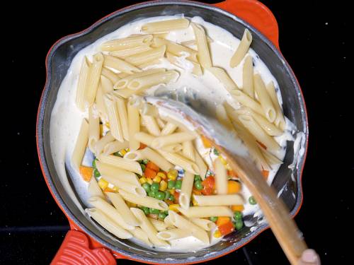 adding veggies to make white sauce pasta