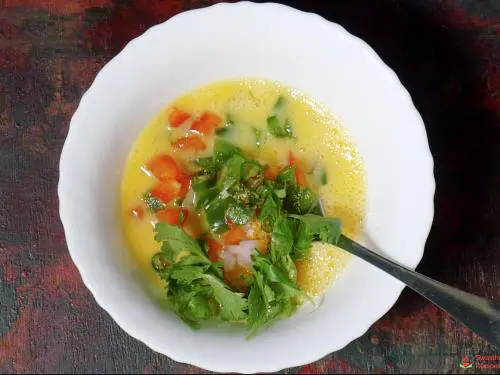 adding veggies and herbs to make bread omelette