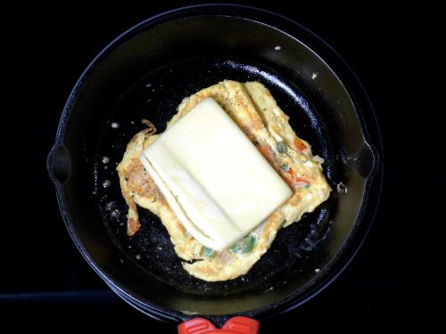 placing a cheese slice over egg