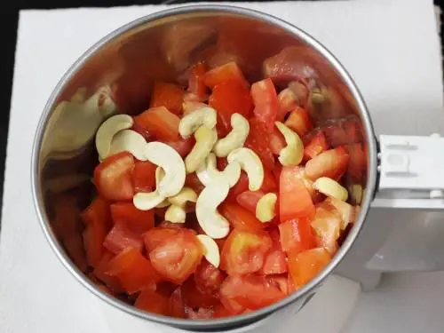 adding tomatoes to blender jar to make paneer makhani
