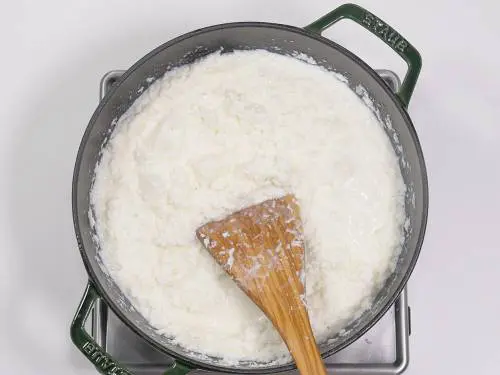 simmering coconut and milk to make coconut burfi