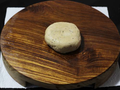 flattened dough ball on a greased board